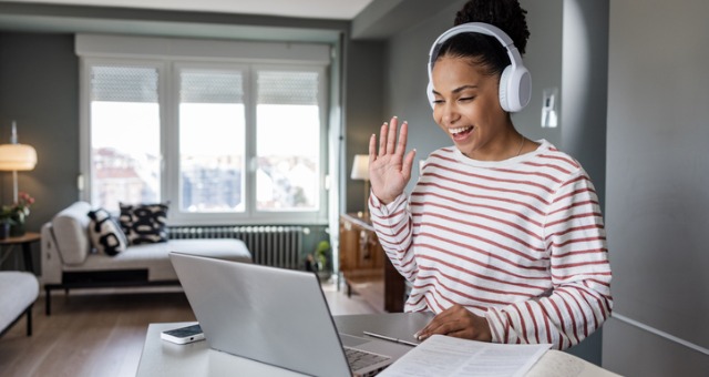 student with headsphones on waving at laptop screen